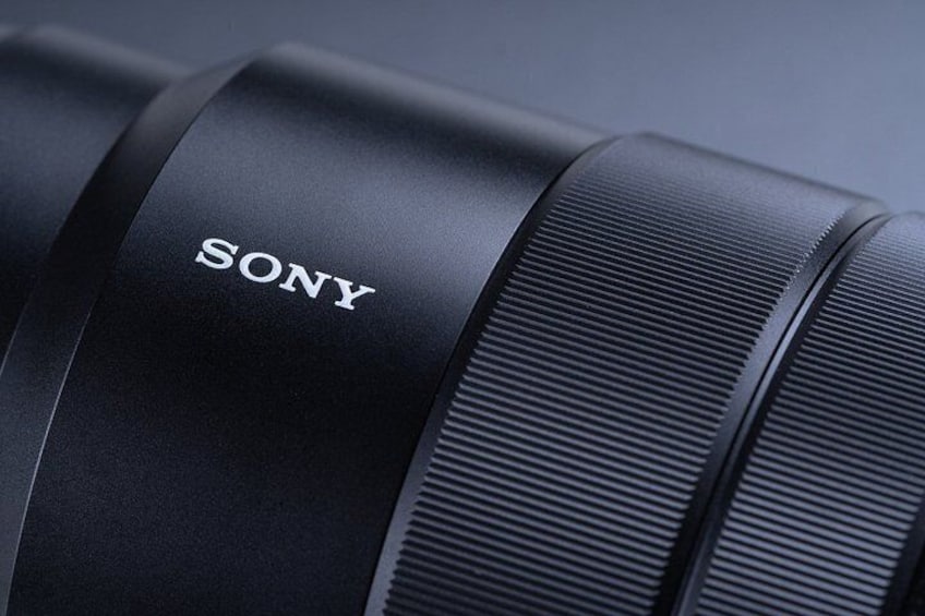 A close-up of a Sony camera lens with a textured grip and a label. 4