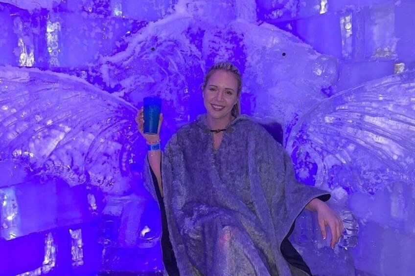 A person seated in a chair with a blue object in hand, surrounded by ice sculptures and a blue-lit environment. 2