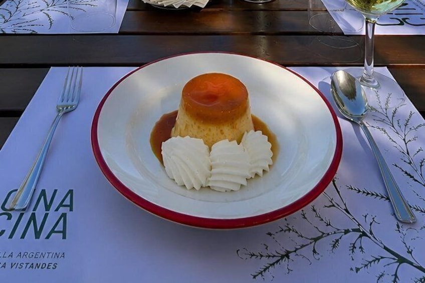 A dessert plate with flan and whipped cream on a table with a placemat. 2