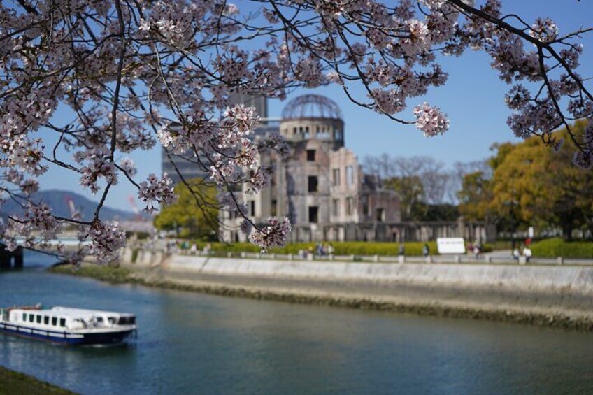 A river with a boat, cherry blossoms, and a historic building with a dome. 3