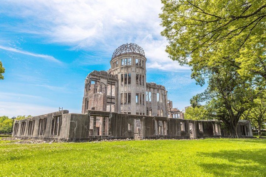 A large, historic building with a dome and multiple windows, surrounded by a grassy field and trees. 2