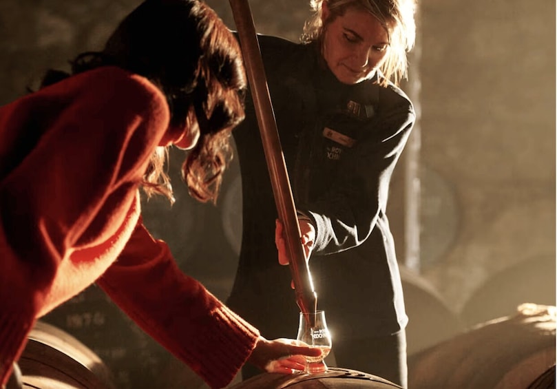 A person pouring a liquid from a bottle into a glass. 1