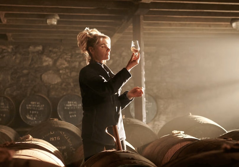 A person holding a wine glass in a cellar with barrels. 2