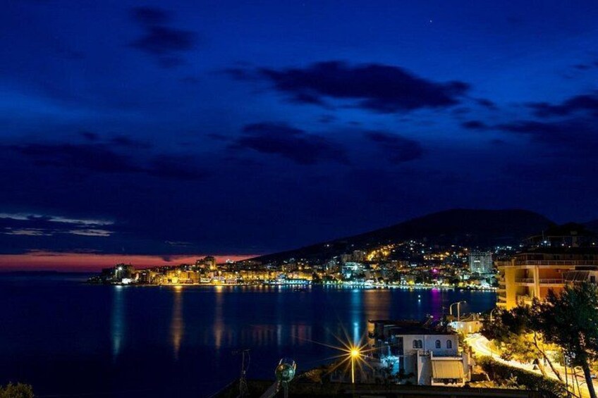 A coastal cityscape at night with illuminated buildings and a calm sea. 4