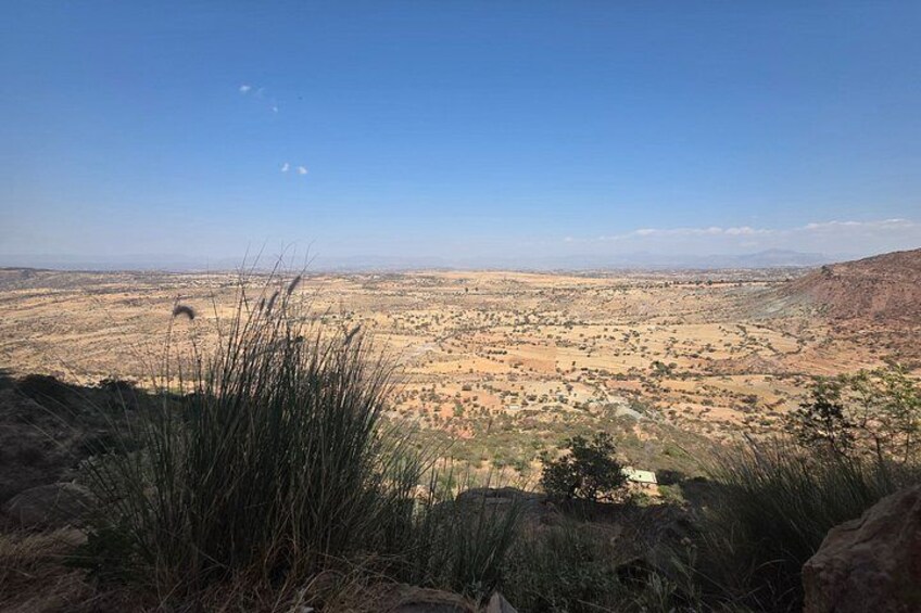 A vast desert landscape with sparse vegetation, distant mountains, and a clear sky. 3