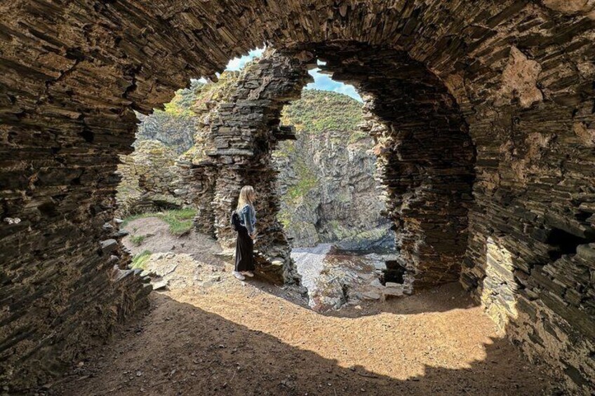 A person standing in a stone archway with a view of a rocky landscape. 4