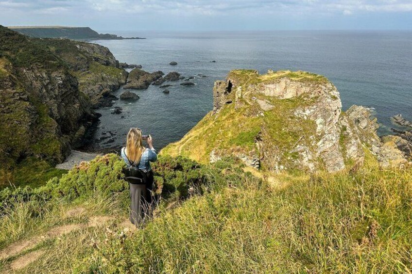 A person taking a photo of a coastal landscape with cliffs and the sea. 5