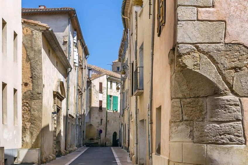 A narrow street flanked by historic buildings with stone facades and arched doorways. 2