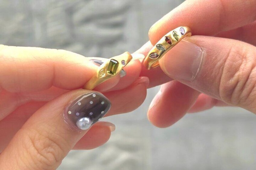 A person holding a gold ring with a gemstone. 5