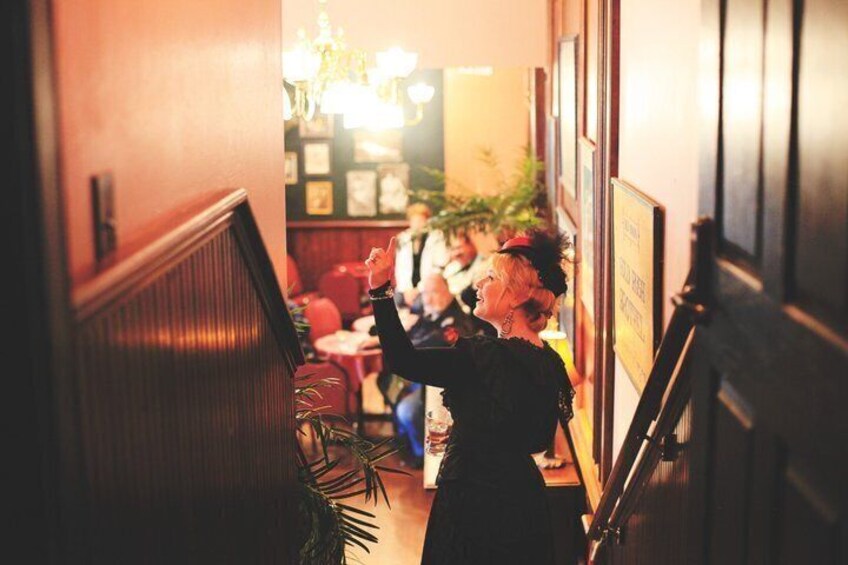 A restaurant interior with wooden booths, a staircase, and a chandelier. 5