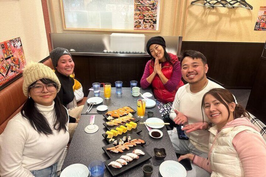 Un groupe de personnes est assis autour d’une table, devant divers plats et boissons. 5