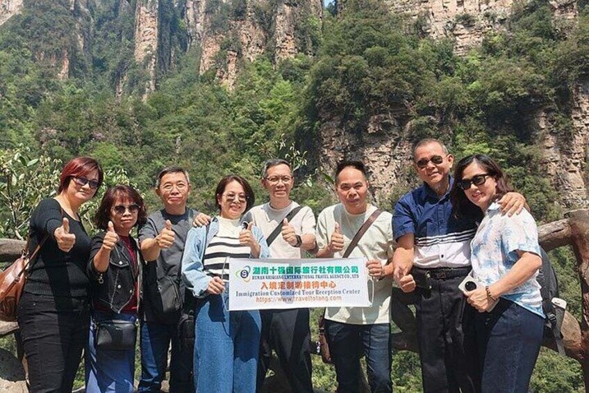 A group of people posing with a sign in a mountainous area. 5