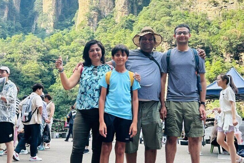 A group of people standing in a mountainous area with greenery and rocky cliffs in the background. 5