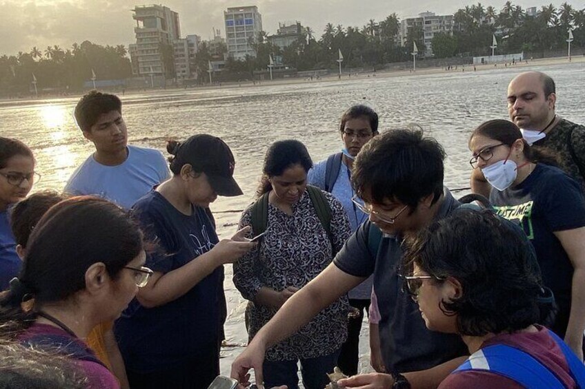 A group of people standing by a waterfront, some looking at a map or device. 5