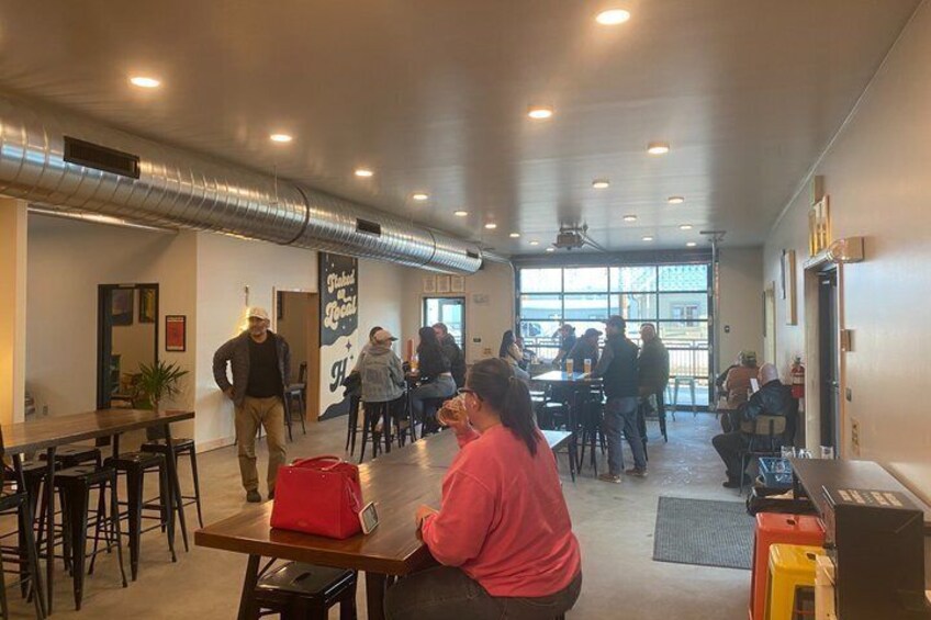 A spacious indoor area with tables and chairs, a red bag on a table, and a person sitting. 3