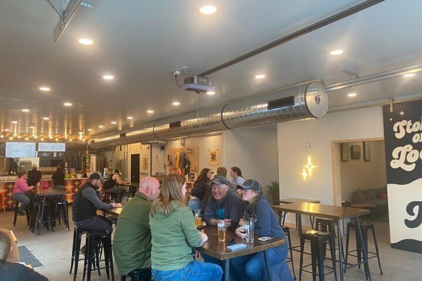 A group of people sitting at tables in a cafe with a bar in the background. 2