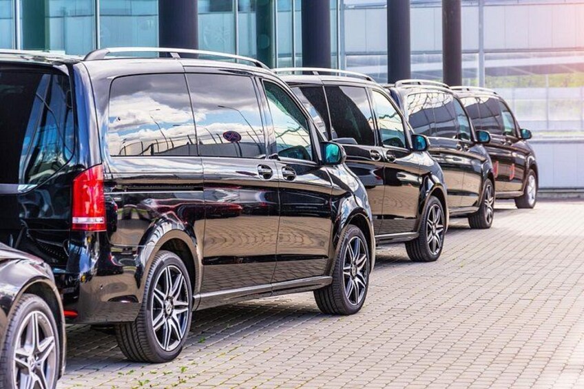 A row of black SUVs parked in front of a building with large windows. 2