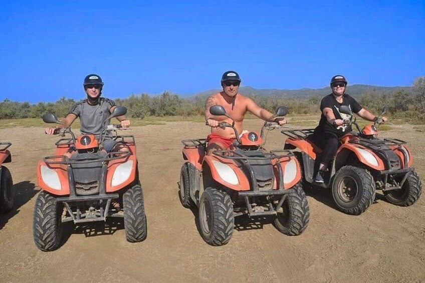 Three people on ATVs in a desert landscape. 2