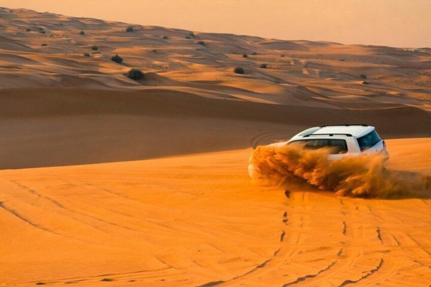 A white SUV driving through a desert with sand dunes. 5