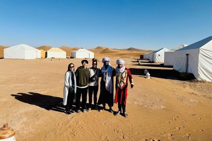Un groupe de personnes se tient debout dans un désert, avec des yourtes en arrière-plan. 4