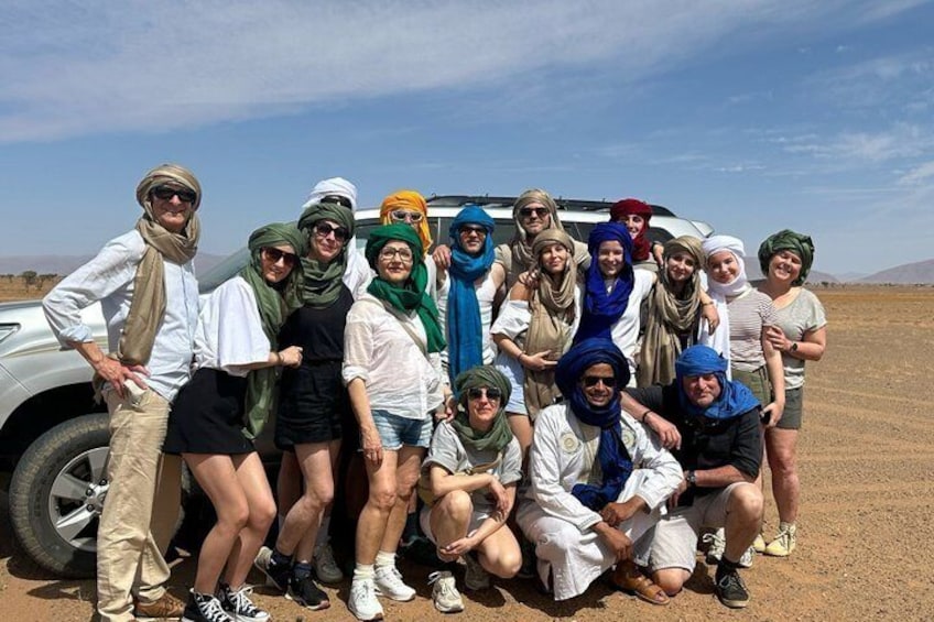 Un groupe de personnes posant devant un véhicule dans un paysage aride et dégagé. 2