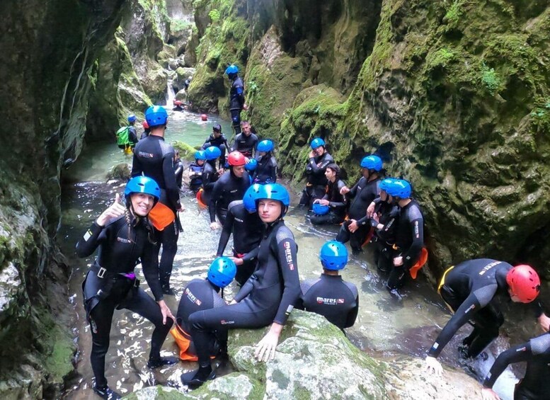 A group of people in wetsuits and helmets preparing for a water activity in a narrow, rocky canyon. 2