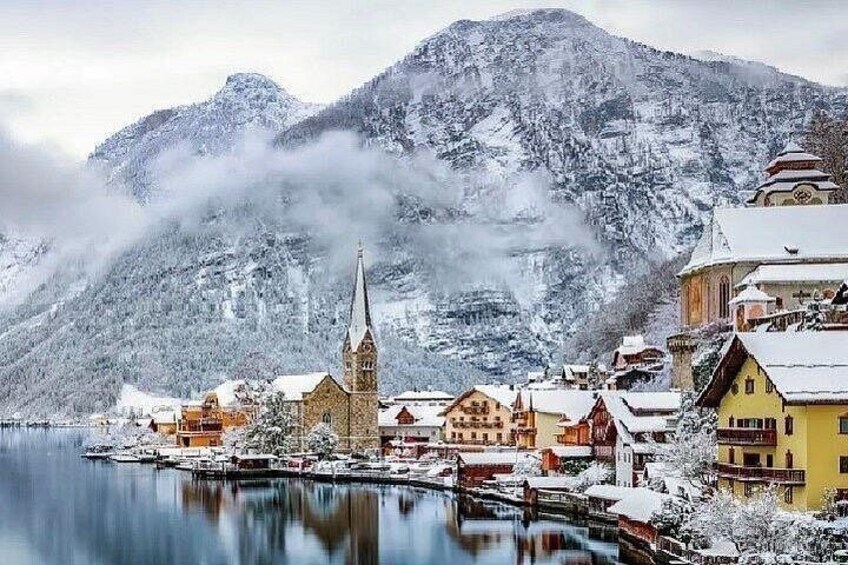 A snow-covered village with a church, houses, and mountains in the background. 2