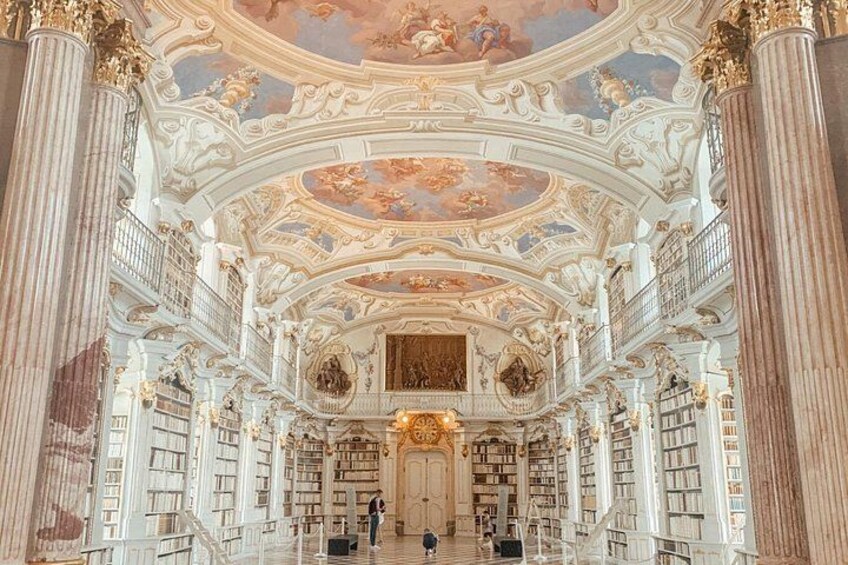An ornate library interior with high ceilings, detailed frescoes, and classical columns. 4