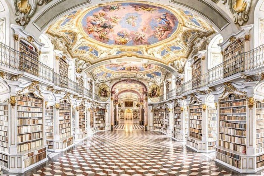 A grand library interior with ornate ceilings, a checkered floor, and tall bookshelves. 4