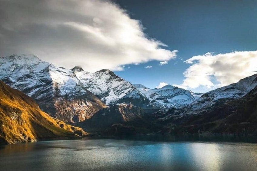A mountain range with snow-capped peaks, a lake, and a clear sky. 3