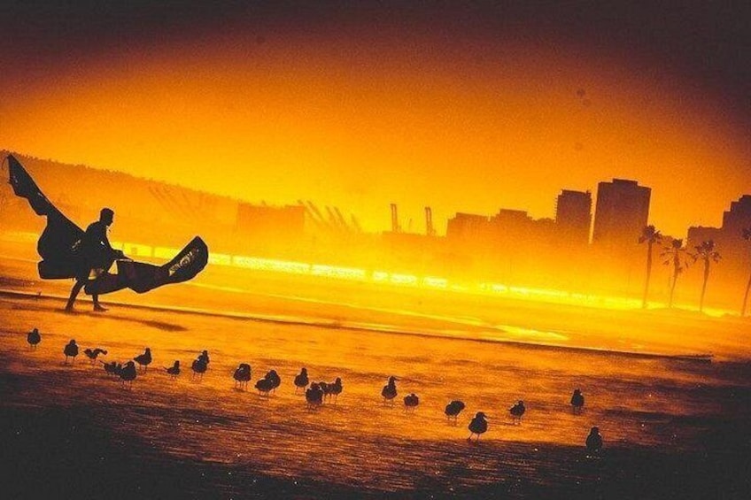 En person som åker skateboard på en strand med en solnedgång i bakgrunden. 4