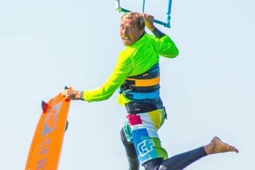 En person i en färgglad klädsel som håller i ett kiteboard. 3
