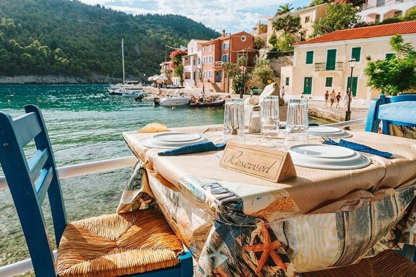 A table set for dining with a 'Reserved' sign, overlooking a coastal town with boats and buildings. 3