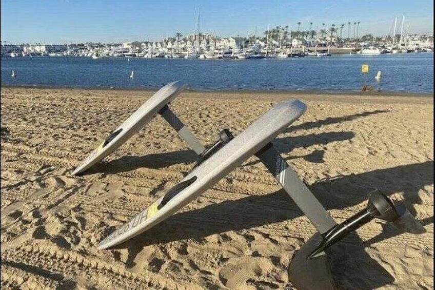 Two sun loungers on a sandy beach with a marina and boats in the background. 5