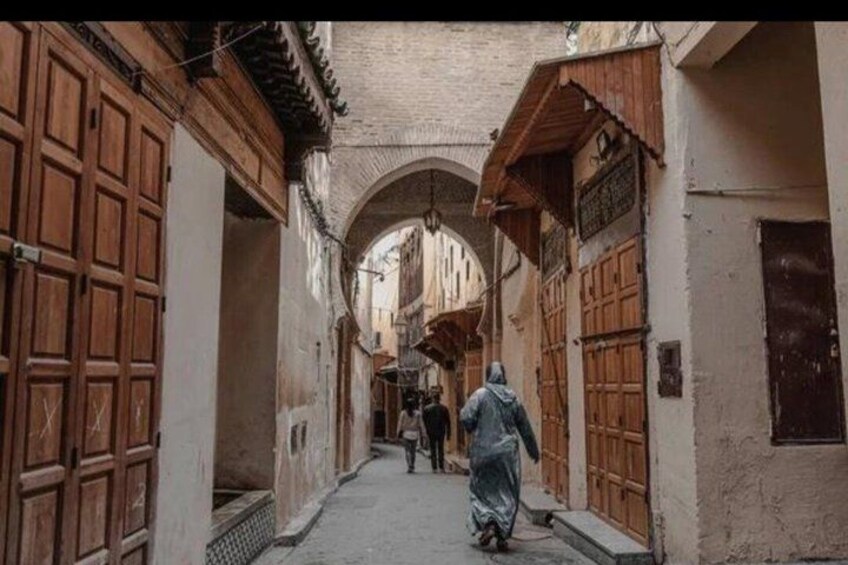 A narrow alleyway with wooden doors and arches. 3