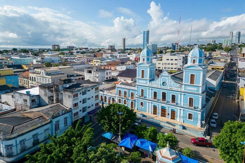 A cityscape with a prominent blue church, a mix of modern and older buildings, and a clear sky. 3