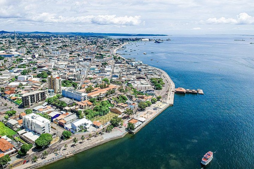 A coastal cityscape with a prominent waterfront, a large body of water, and a distant bridge. 1