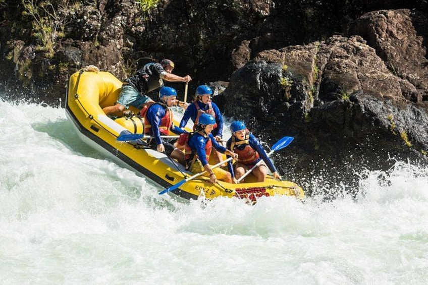 A group of people rafting on a yellow inflatable raft in a river. 1