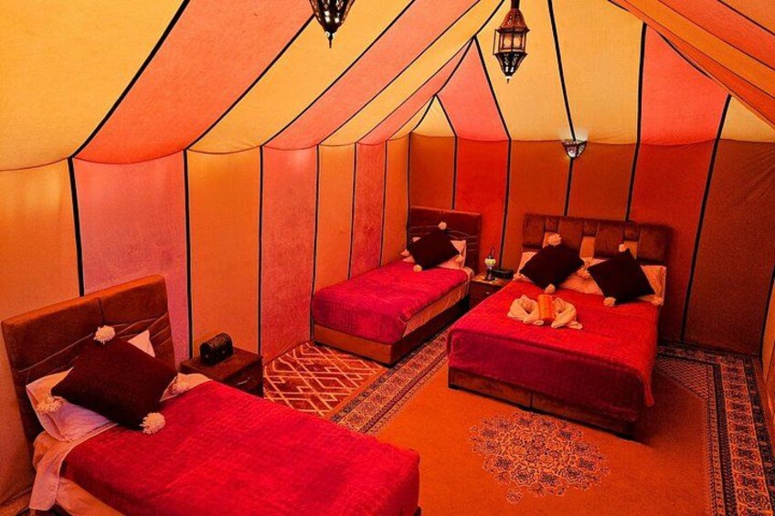A tent with two beds, each with red bedding and pillows. 5