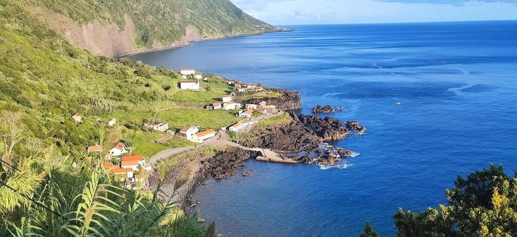 A coastal village with houses, a rocky coastline, and a clear blue sea. 1