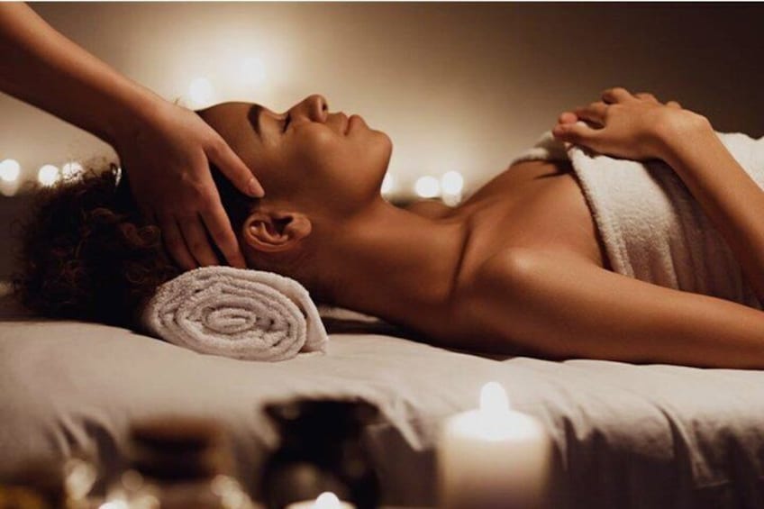 Een persoon ontvangt een massage, met een handdoek en kaarsen op de achtergrond. 4