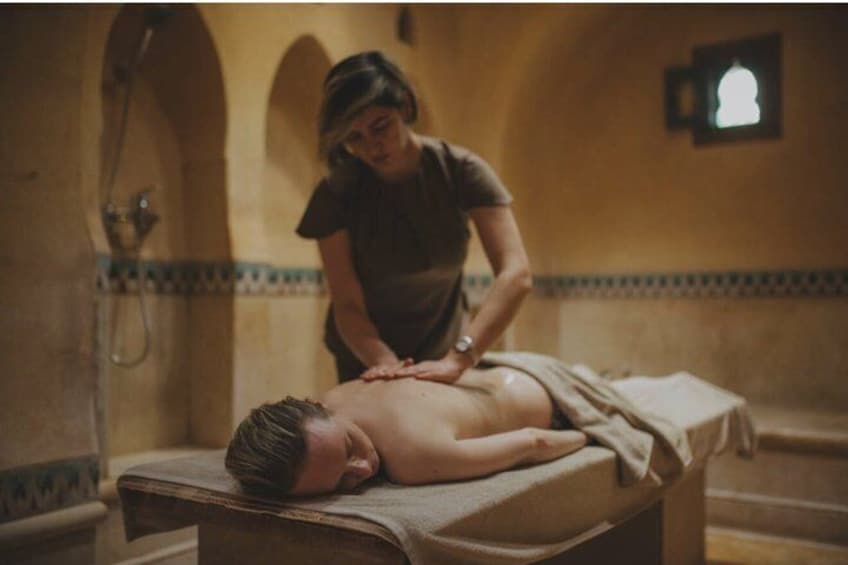 Iemand ontvangt een massage in een kamer met een betegelde muur en een douche. 5
