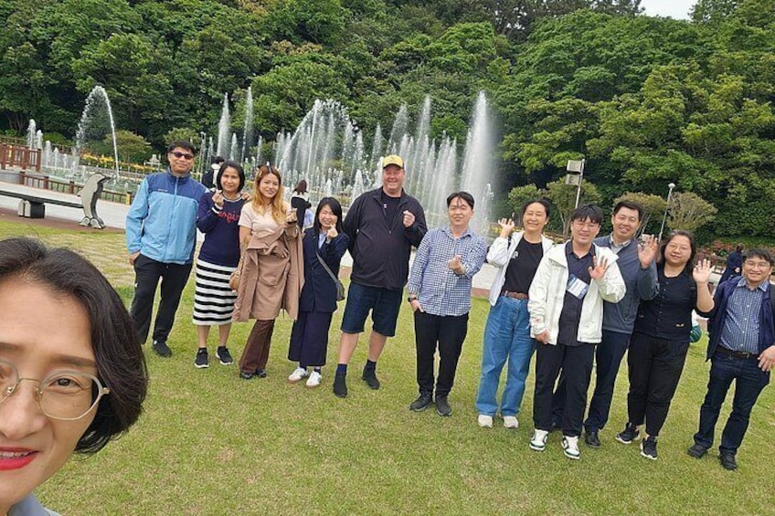 A group of people standing in a park with fountains in the background. 2
