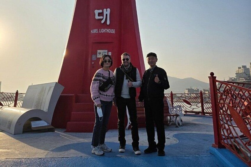 A red monument with a sign reading 'HANEL LIGHTHOUSE' and a person standing in front of it. 4