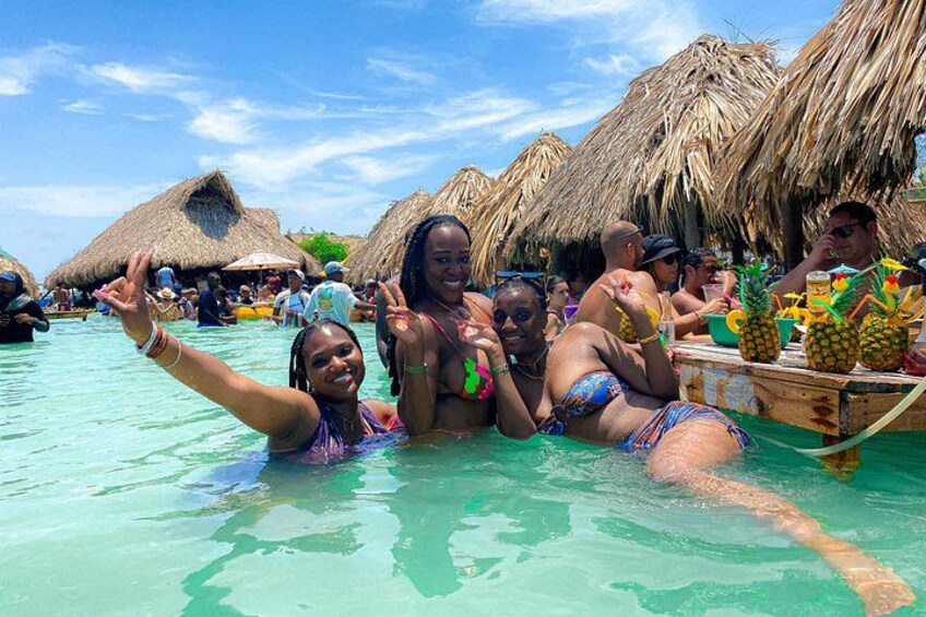 People in a tropical setting with thatched-roof huts and a wooden boat. 5