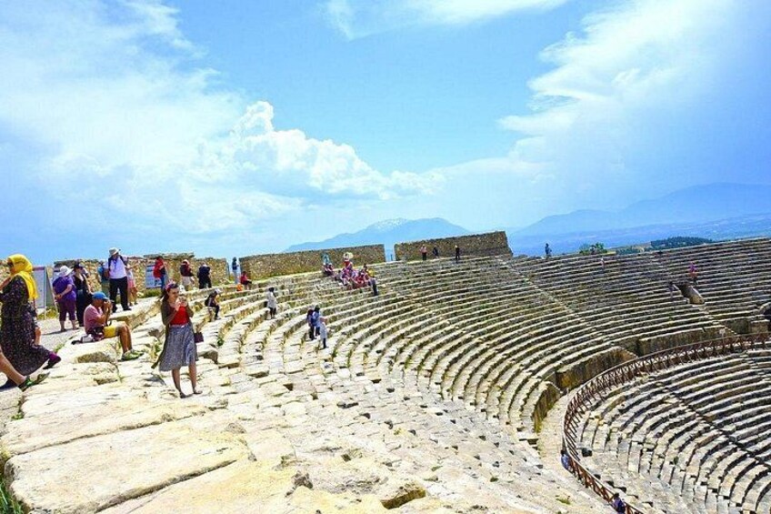 An ancient amphitheater with stone seating and a clear sky. 2