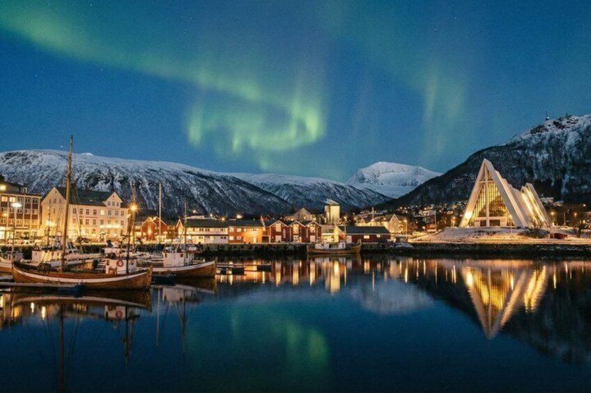 A harbor with boats, buildings, and a snow-covered mountain under the aurora borealis. 2