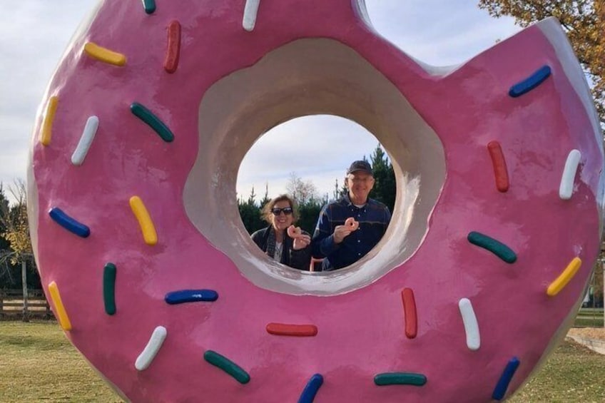 A large pink donut with a hole in the center, surrounded by colorful sprinkles. 2