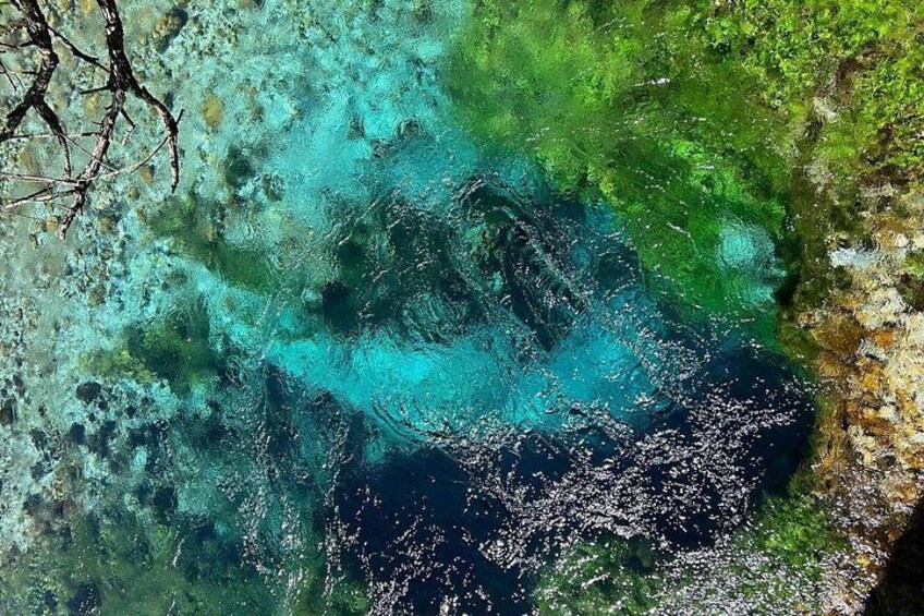 A clear blue sea with visible underwater rocks and coral formations. 2
