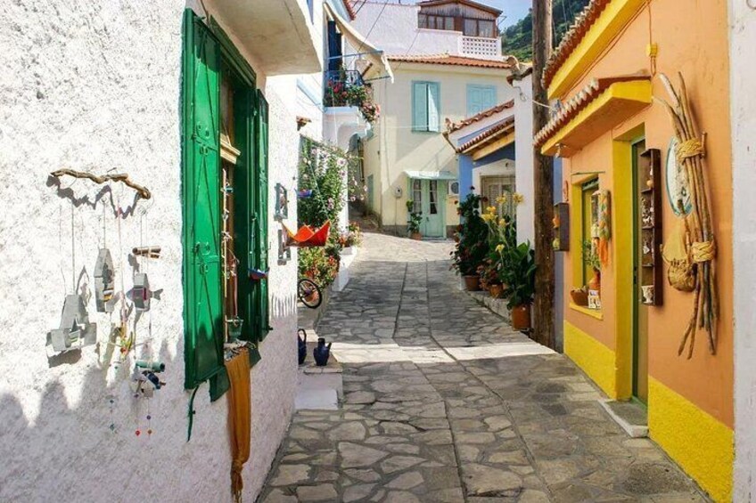 A narrow cobblestone street flanked by buildings with colorful facades and hanging decorations. 4